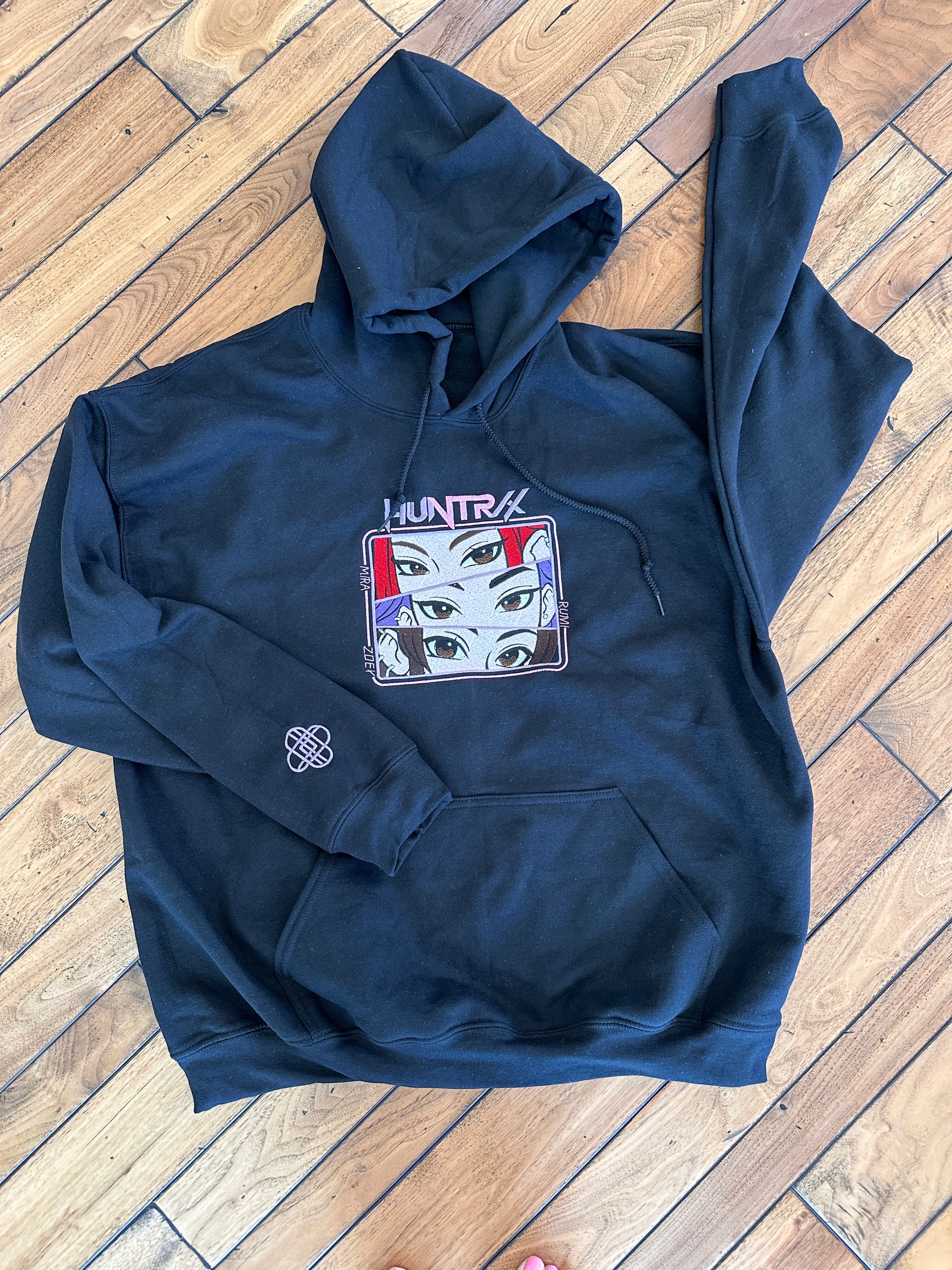 Black hoodie with graphic design on a wooden floor