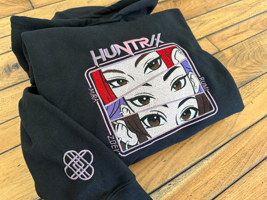 Black hoodie with 'HUNTRIX' design on a wooden floor