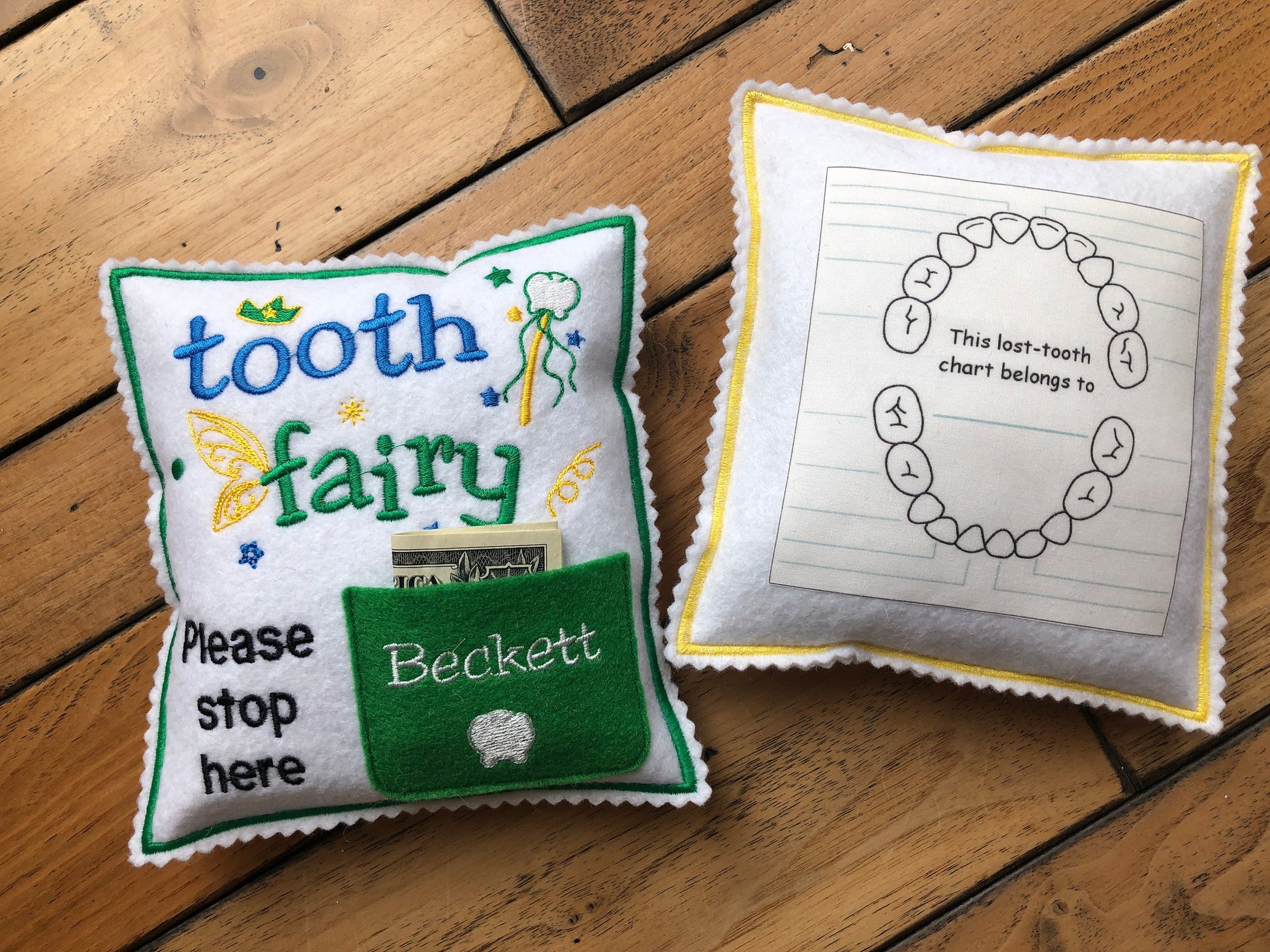 Green and blue Tooth fairy pillow with embroidered details.  It has a pocket for tooth exchange.  Personalized with the child's name embroidered on the pocket.  In the back it has a tooth chart to keep track of the dates of the lost teeth.