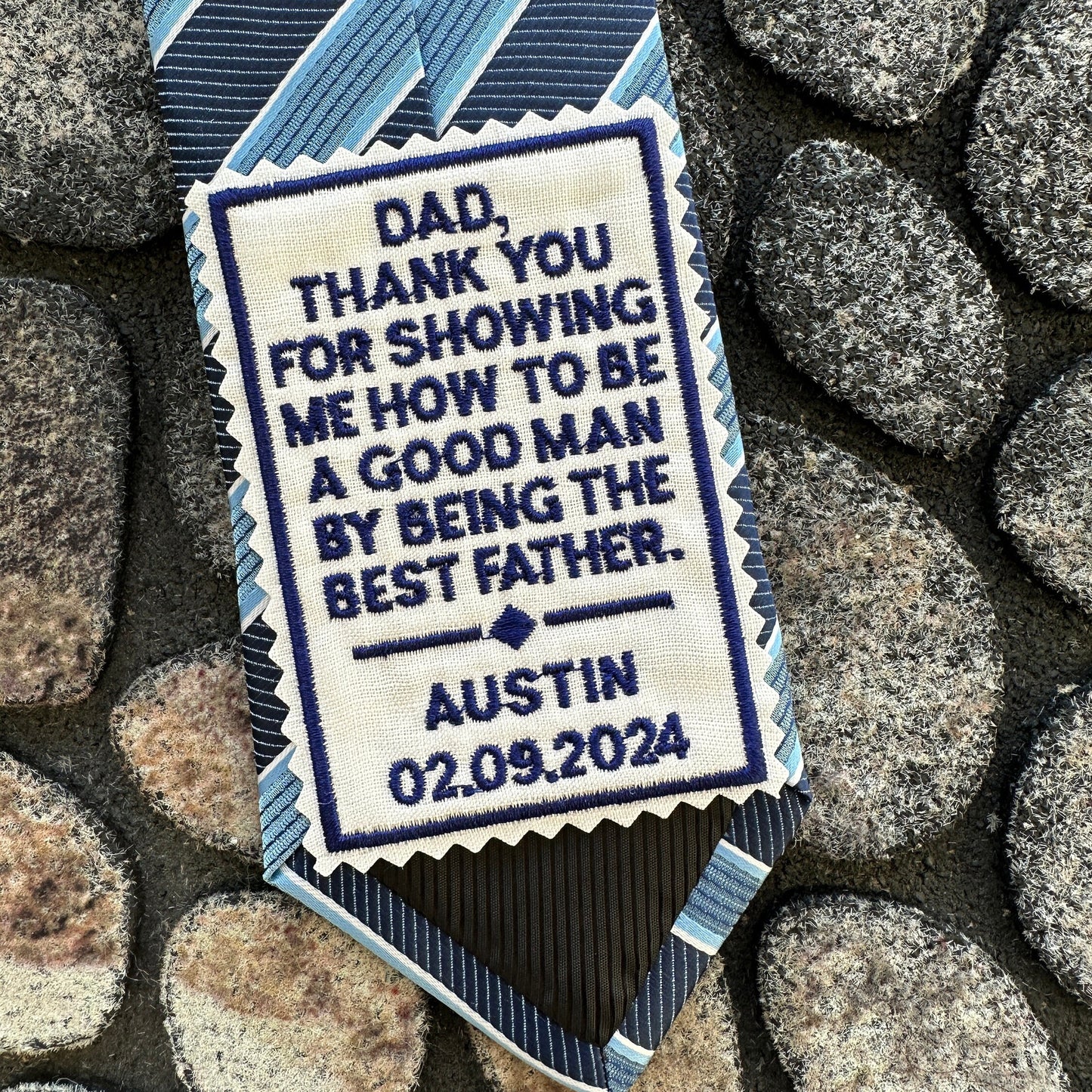 Personalized tie with embroidered message on a stone background