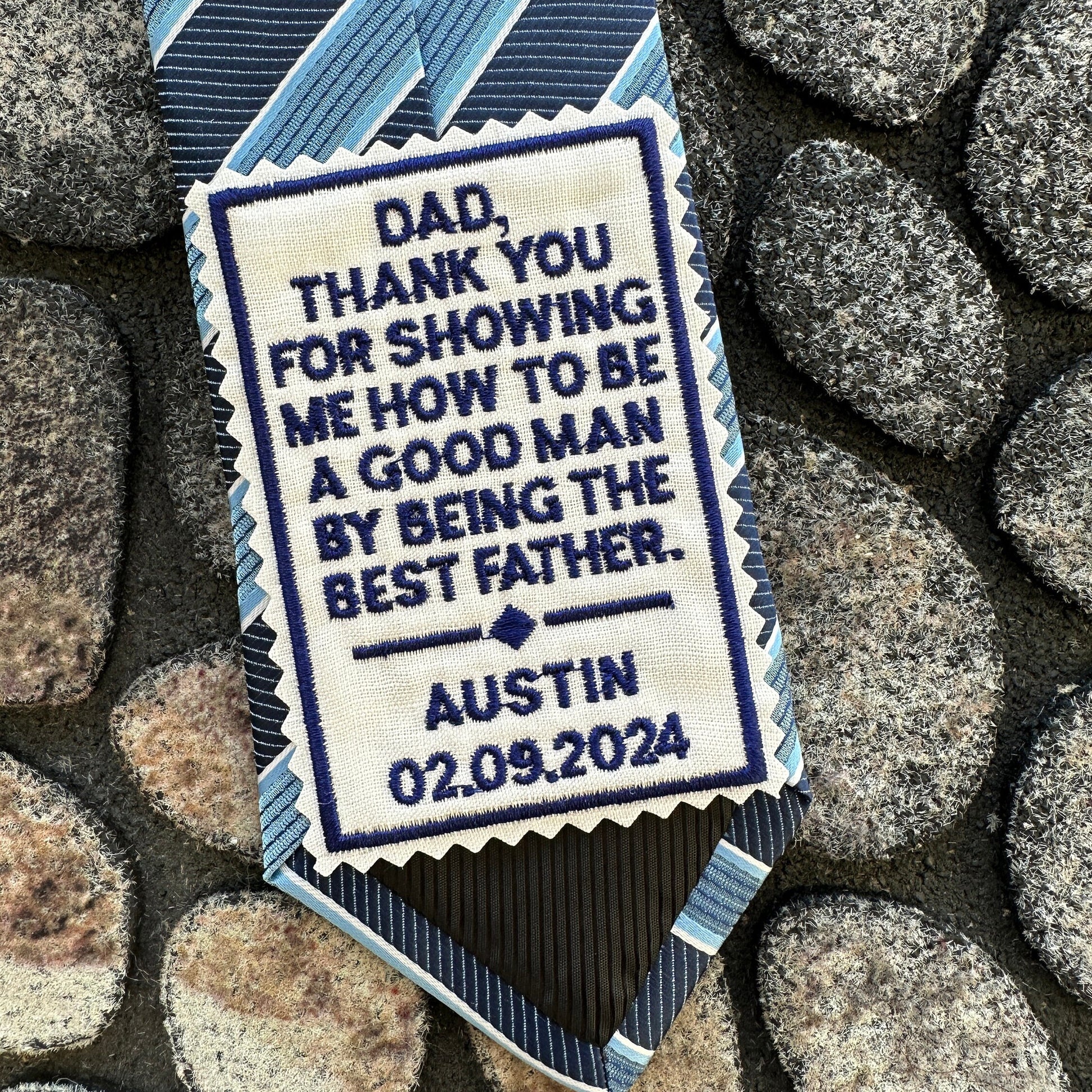 Personalized tie with embroidered message on a stone background