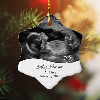A snowflake-shaped Christmas ornament featuring a baby ultrasound photo, personalized with the baby's family name and the year of birth, perfect for celebrating a baby's first Christmas or as a keepsake.