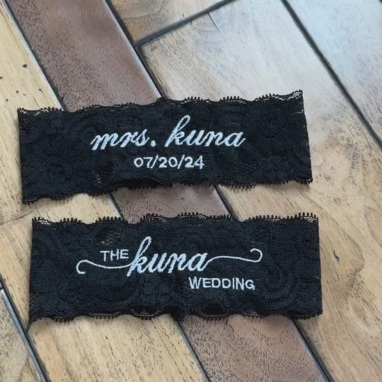 a set of black bridal lace garter with custom embroidery on a wooden background