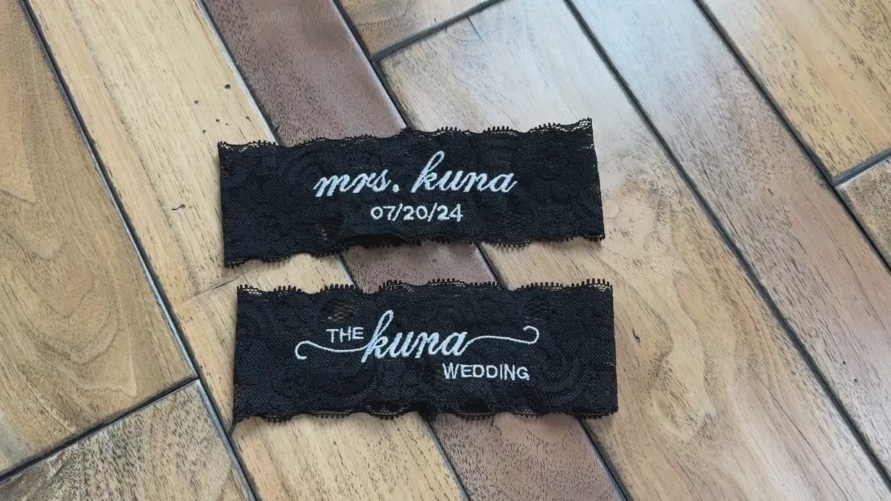 a set of black bridal lace garter with custom embroidery on a wooden background